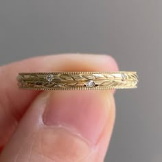 a close up of a person's hand holding a gold ring with diamonds on it