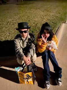 two people sitting on the ground with one holding a bag and the other pointing at something