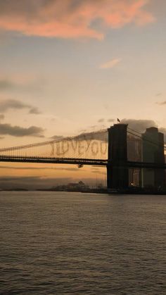 an image of a bridge that is going over the water at sunset or dawn with clouds in the sky