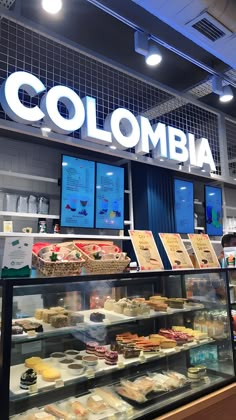 a display case filled with lots of different types of cakes and pastries in front of a sign that says colombia