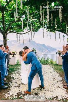 a bride and groom kissing under a tree