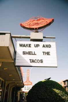 a neon sign that says wake up and smell the tacos on top of a building