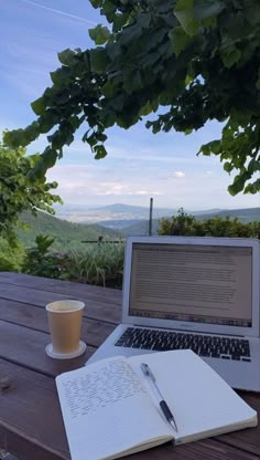 an open laptop computer sitting on top of a wooden table next to a cup of coffee