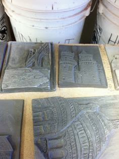 four cement coasters sitting on top of a table next to trash cans and buckets