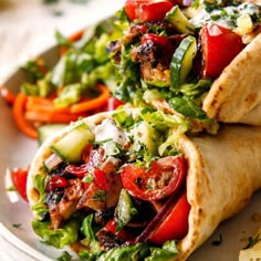 two burritos on a plate topped with vegetables