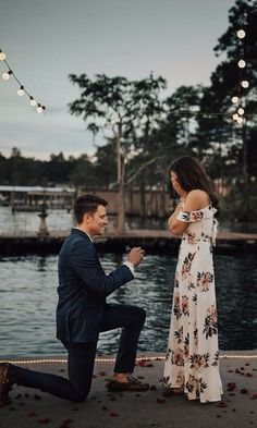 a man kneeling down next to a woman who is holding her hand out for him