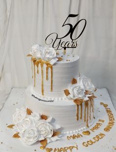 a white wedding cake with gold decorations and the number fifty years on it's side