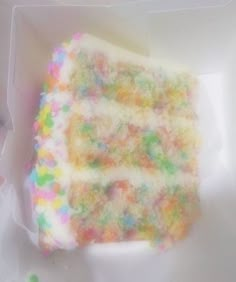 a piece of cake with sprinkles on it sitting in a white box