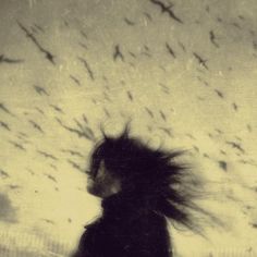 a blurry photo of a woman with birds flying in the sky over her head