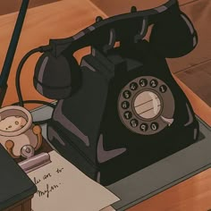 an old fashioned telephone sitting on top of a desk next to a pen and paper