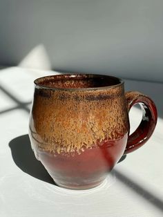 a brown and red cup sitting on top of a white table