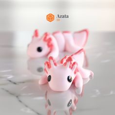 three little pink toy animals sitting on top of a table next to eachother