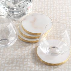 four white and gold plates sitting on top of a table next to a bottle of alcohol