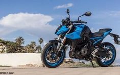 a blue and black motorcycle parked on the side of a road with palm trees in the background