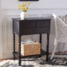 a black table with two drawers and a wicker basket under it next to a white chair