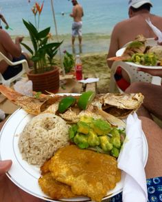 a white plate topped with lots of food on top of a beach