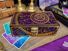 a purple and gold box sitting on top of a wooden table next to cards, money and other items