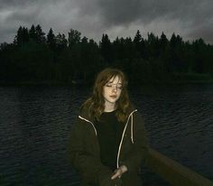 a woman is standing on a dock in front of the water with her eyes closed