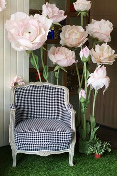 a chair sitting next to a bunch of flowers on top of a green grass covered field