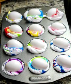 a muffin tin filled with lots of colorful icing