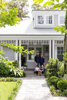 two men and a dog standing in front of a house