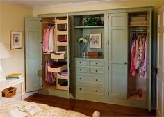 an open closet in a bedroom with clothes hanging on the walls and drawers below it