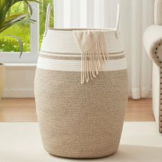 a large white and beige basket sitting on top of a rug next to a window