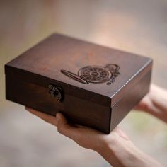 a hand holding a wooden box with an image on it