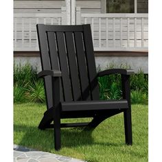 a black chair sitting on top of a lush green field next to a white house