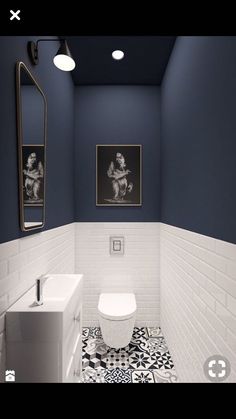 a white toilet sitting next to a sink in a bathroom under two pictures on the wall