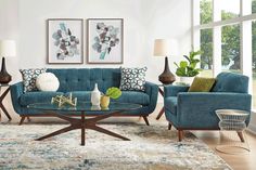 a living room filled with blue couches and pillows on top of a wooden table