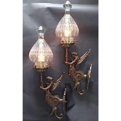 two wall sconces with glass shades on the top and one light attached to it