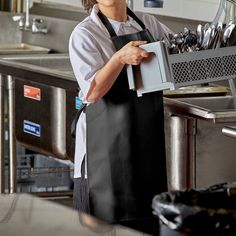 a woman in an apron is holding a box with silver spoons and utensils