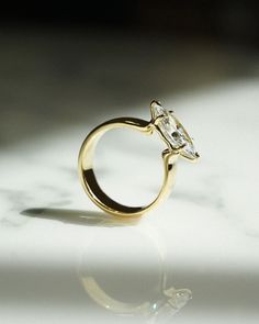 a gold ring with a single diamond on it's side sitting on a white surface