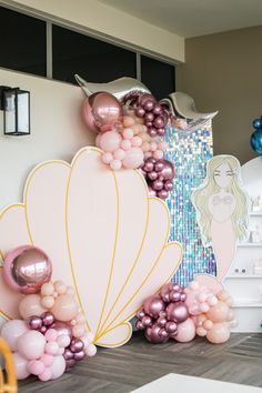 a room with balloons, mermaid tail and other decorations on the wall in front of it