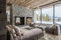 a bedroom with a stone fireplace and large windows overlooking the snow covered mountain side area