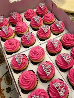 cupcakes with pink frosting in a box decorated with silver and diamond decorations