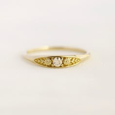 a yellow gold ring with three small flowers on the side and a single diamond in the middle