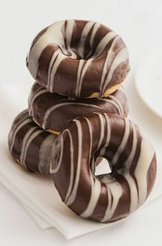 three chocolate covered donuts stacked on top of each other next to a white plate