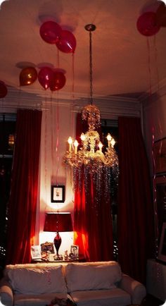 the living room is decorated with red balloons and chandelier hanging from the ceiling