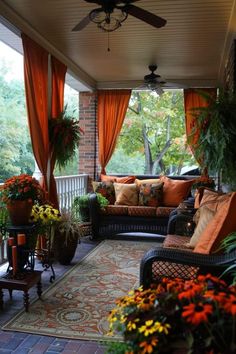 an outdoor living area with couches and plants on the porch, covered in orange drapes