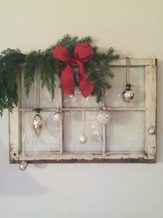 an old window with ornaments hanging on it and a red bow tied to the top