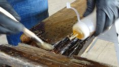 a person in black gloves is pouring something into a container on a piece of wood