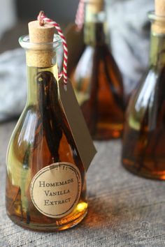 three small bottles with labels on them sitting on a table next to some other bottles