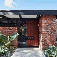 the entrance to a brick house with plants in front