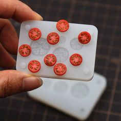 a person holding a plastic container with small red tomatoes in it's middle, on top of a cutting board