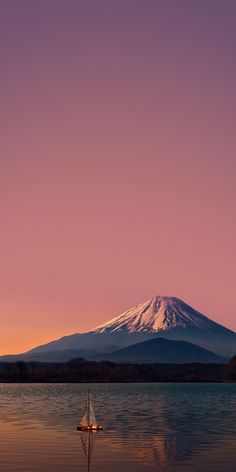 a boat floating on top of a body of water under a snow covered mountain in the distance