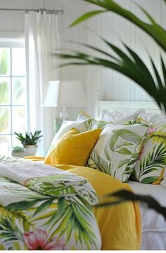 a bed with yellow and green pillows on top of it next to a potted plant