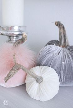 three different colored pumpkins sitting on a table next to a candle and some other decorations