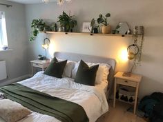 a bed with white sheets and green pillows in a small room next to a window